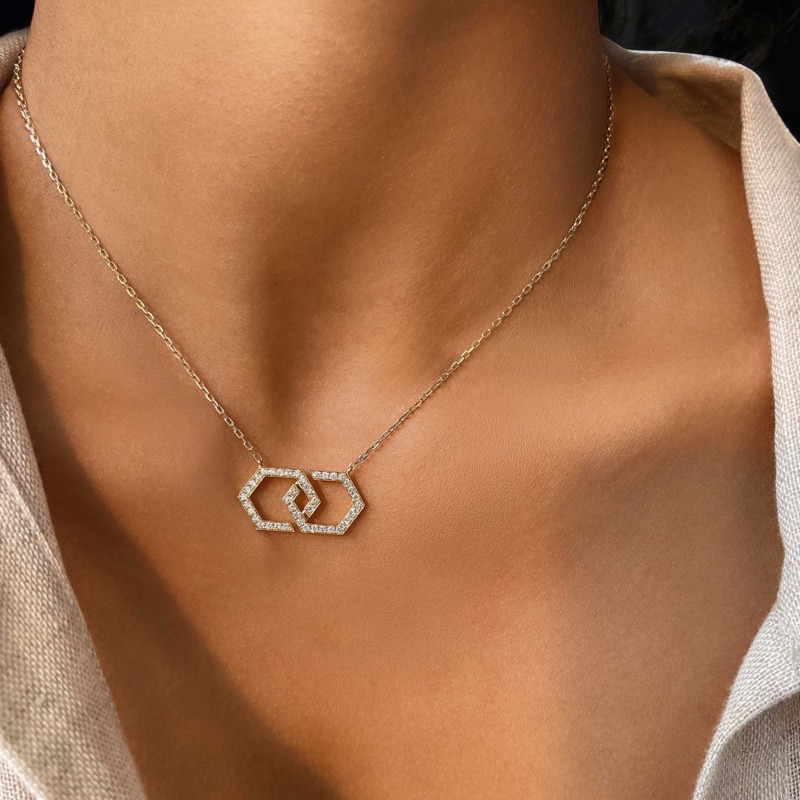 إطلالة على سلسلة Infinity Necklace ذهبية مرصّعة بالكامل بتصميم شكل إنفينيتي، مع تفاصيل حجرية لامعة على طول السلسلة