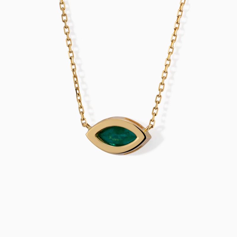 A gold chain necklace holds an eye-shaped green emerald pendant with a polished marquise frame on white.