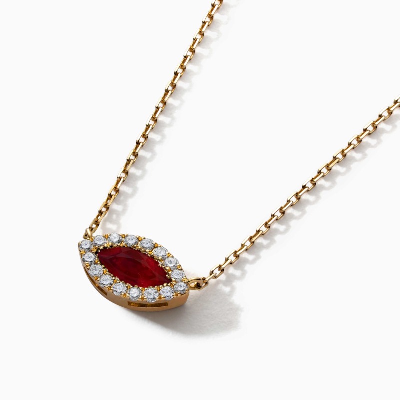 A gold necklace with a marquise ruby pendant bordered by diamonds rests on a clean white background.