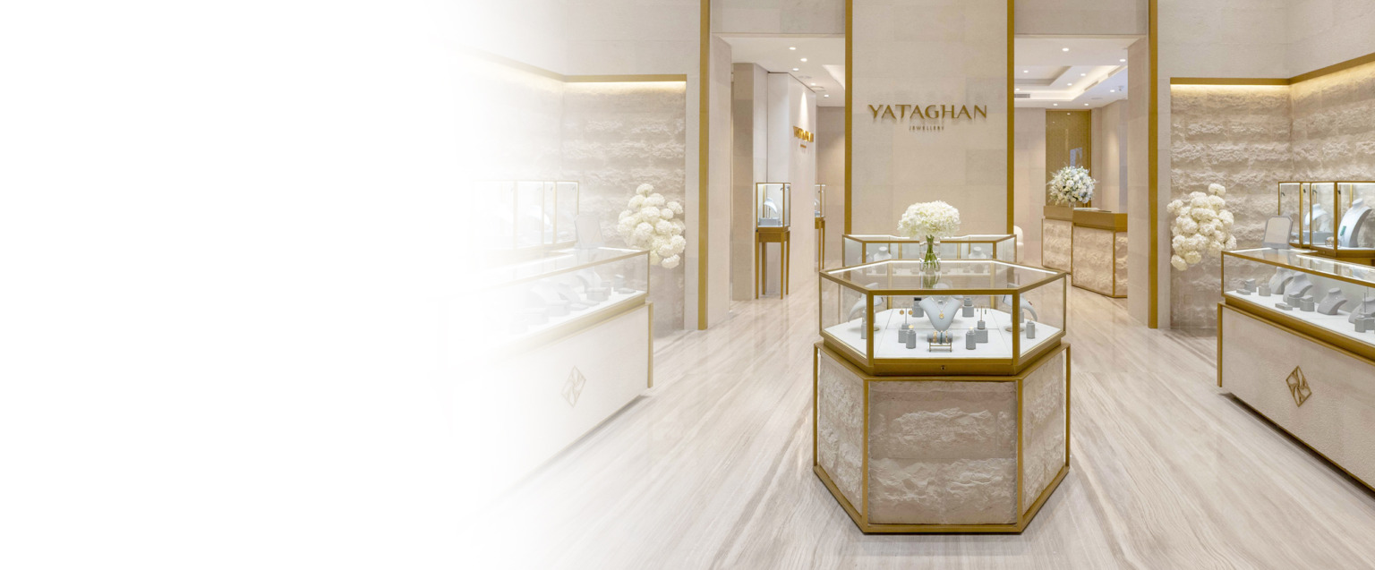 Inside the YATAGHAN Jewellery boutique, gold-framed glass displays and white floral arrangements create a refined showroom.