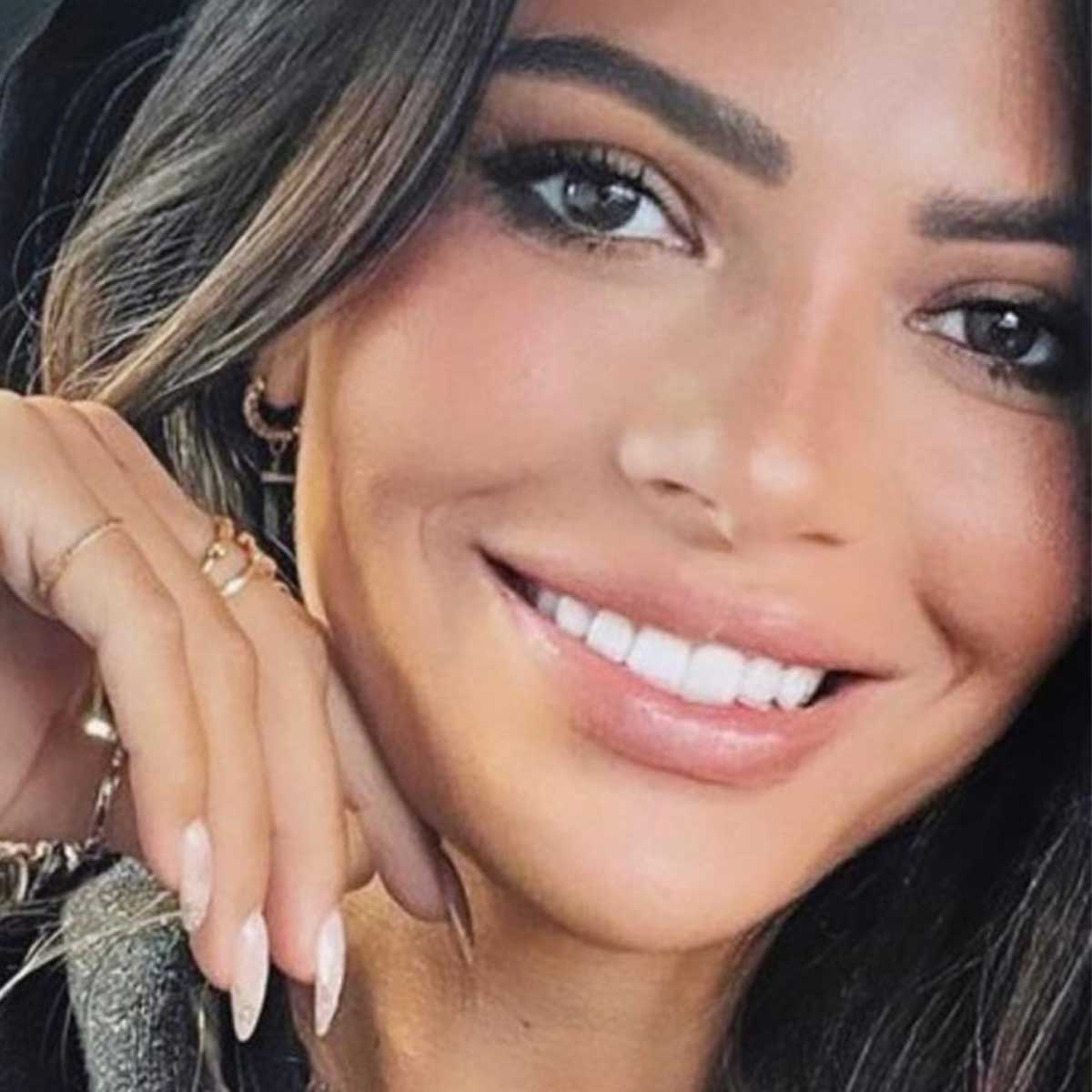 Smiling Fozaza jewellery model for Yataghan Jewellery with gold hoop earrings and long dark hair, close-up portrait with subtle glam makeup details