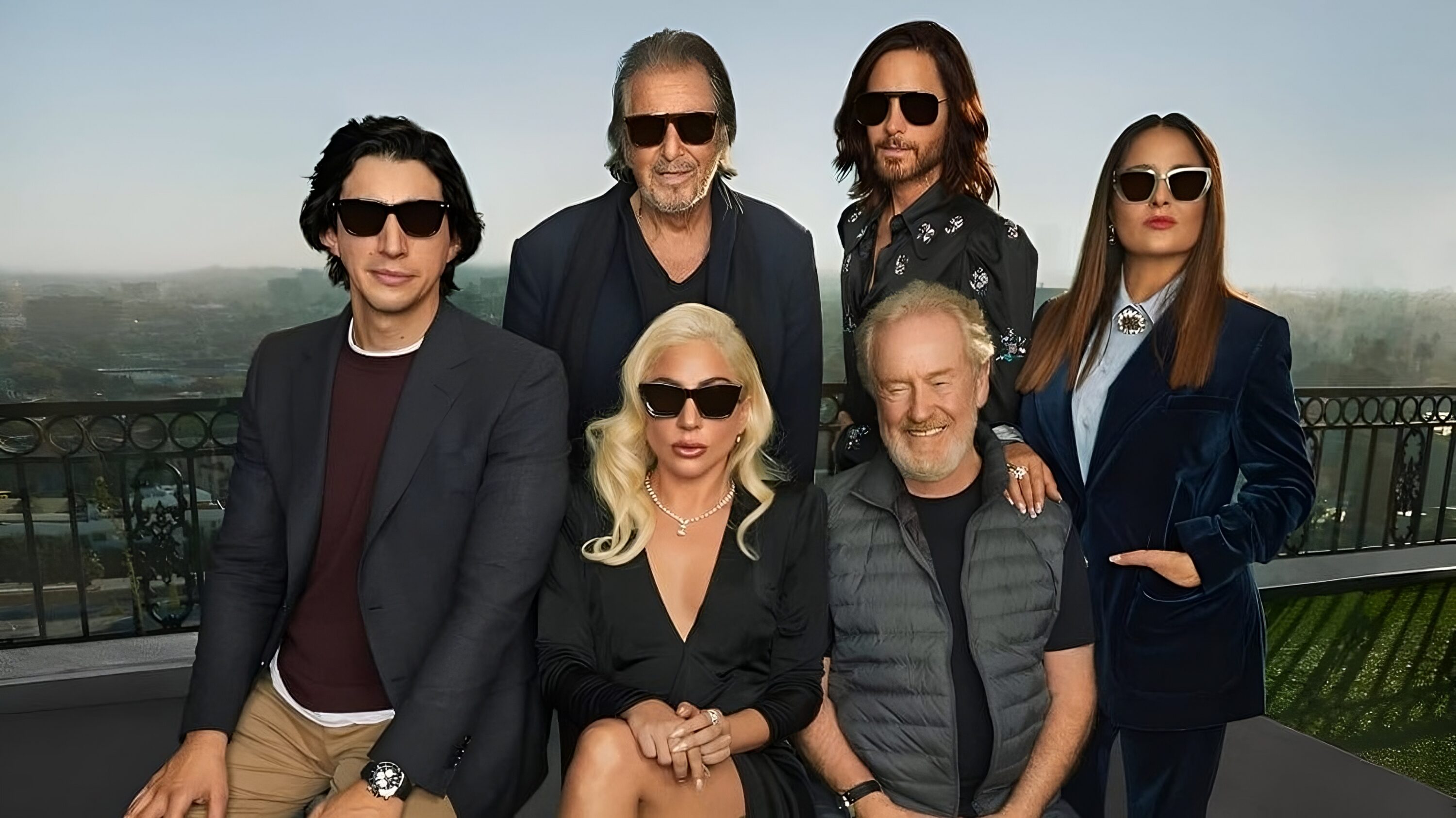 Lady Gaga wearing black sunglasses with dark outfits in an outdoor setting, standing with a group dressed in black and sunglasses.
