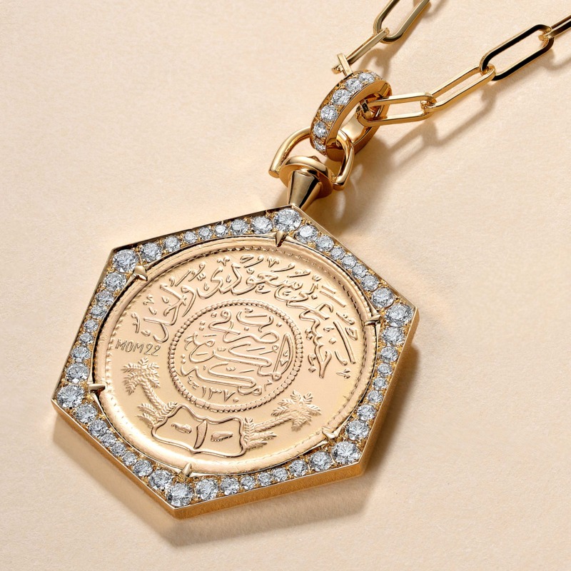 A Full Ginea Necklace in Diamonds with a gold bail and clasp, featuring a detailed engraved centerpiece and a border of diamonds.