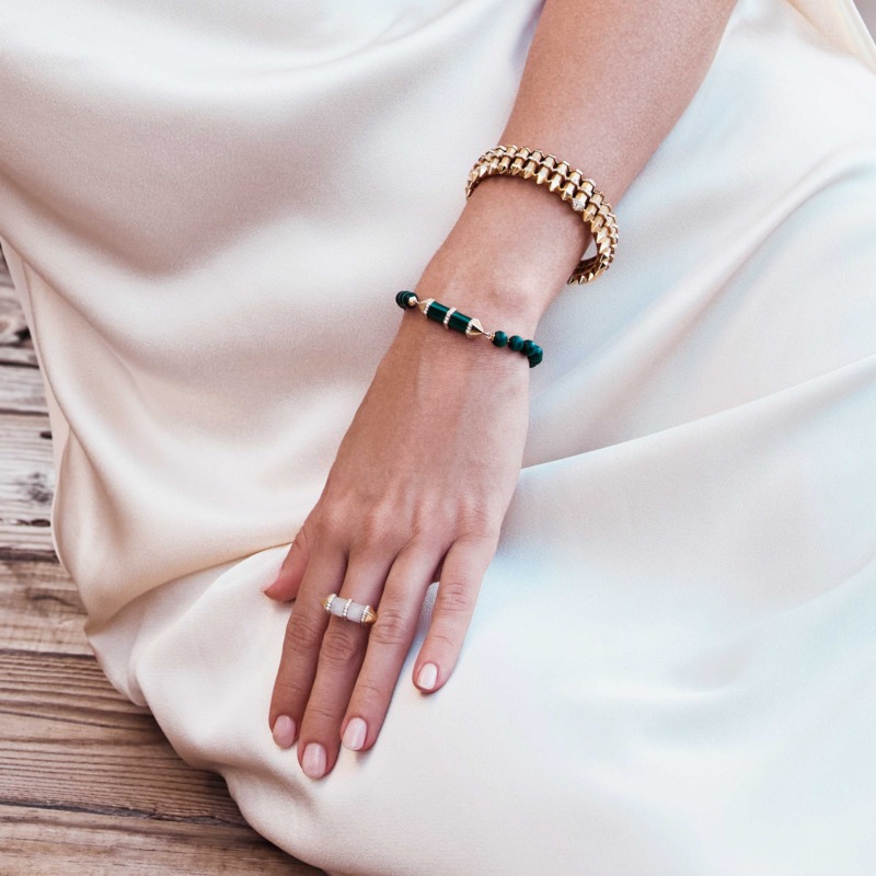 Chakra Graduated Gold Cuff from Yataghan Jewellery sits on a wrist with layered bracelets, in a refined gold finish and graduated design.