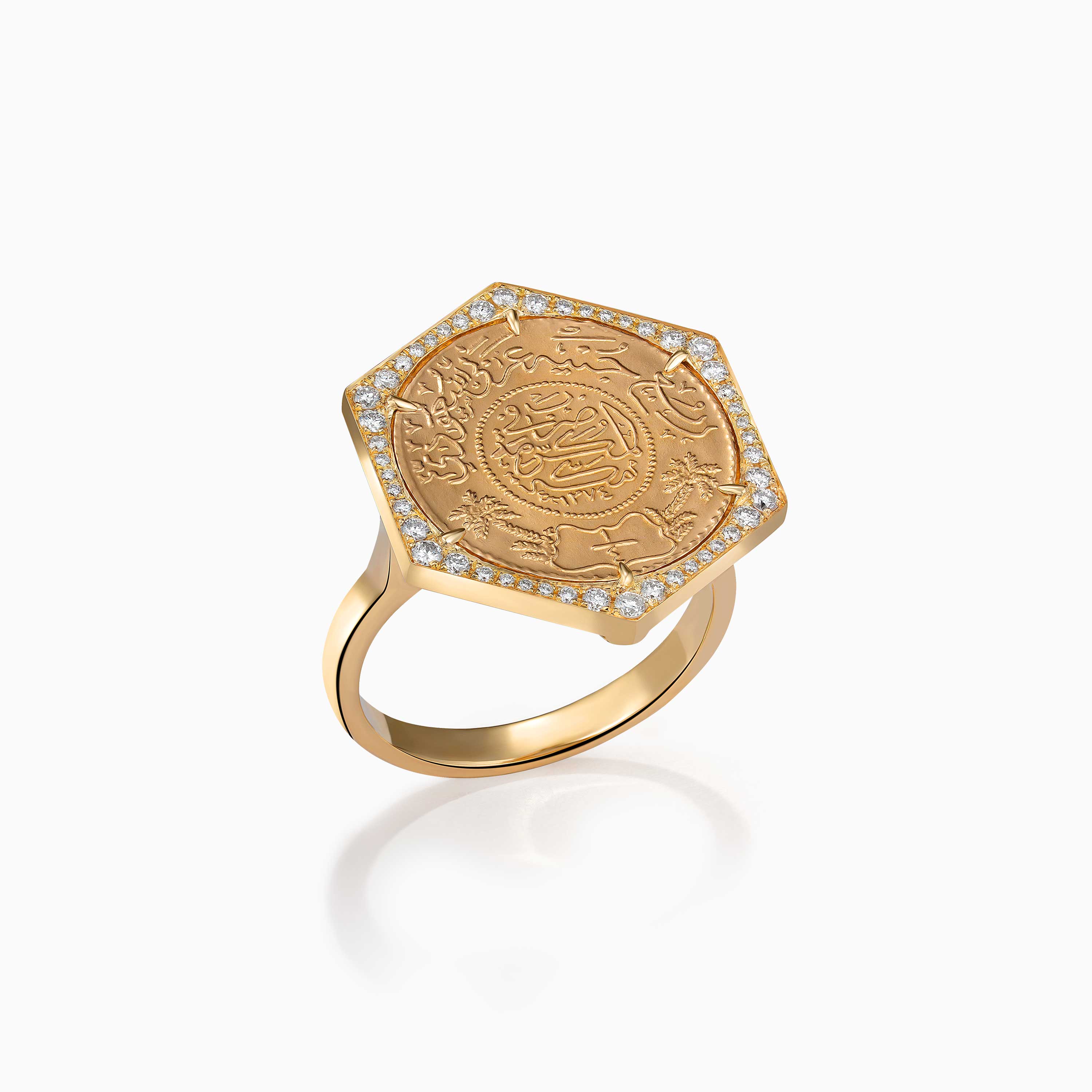 A gold Ginea Ring by Yataghan Jewellery with an engraved coin motif, set in a diamond frame and secure prong border.