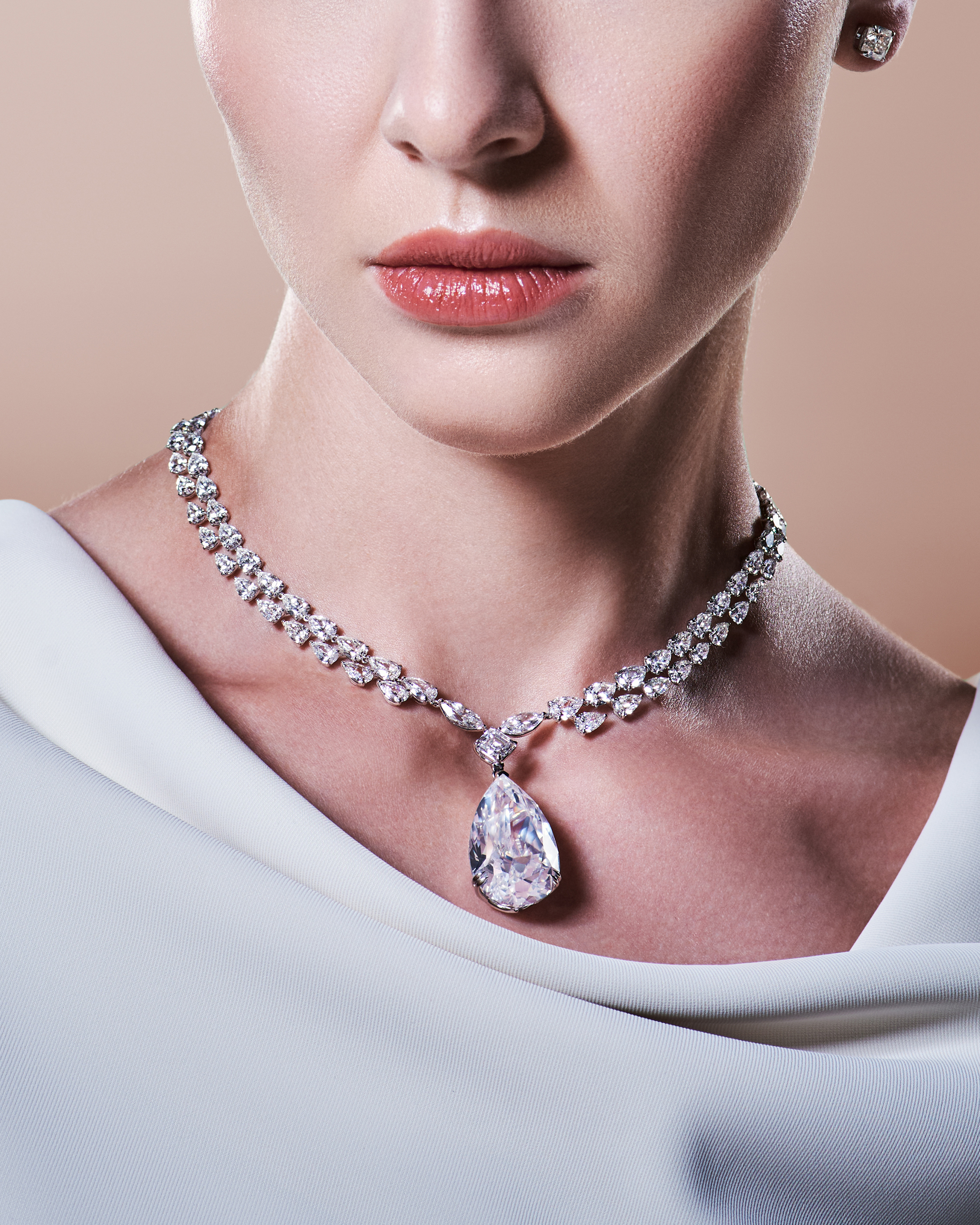 An elegant diamond necklace with a large pear-shaped pendant rests against a model's neckline, reflecting Yataghan Jewellery high jewellery craftsmanship.