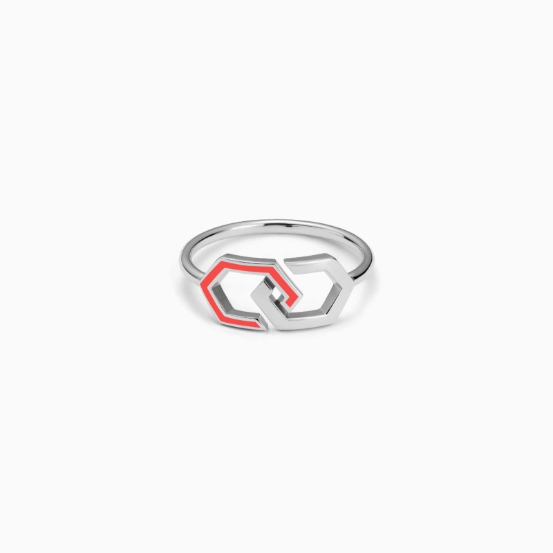 A polished Infinity Enamel Gold Ring Band with linked geometric shapes and bright pink-orange enamel rests on a white background.