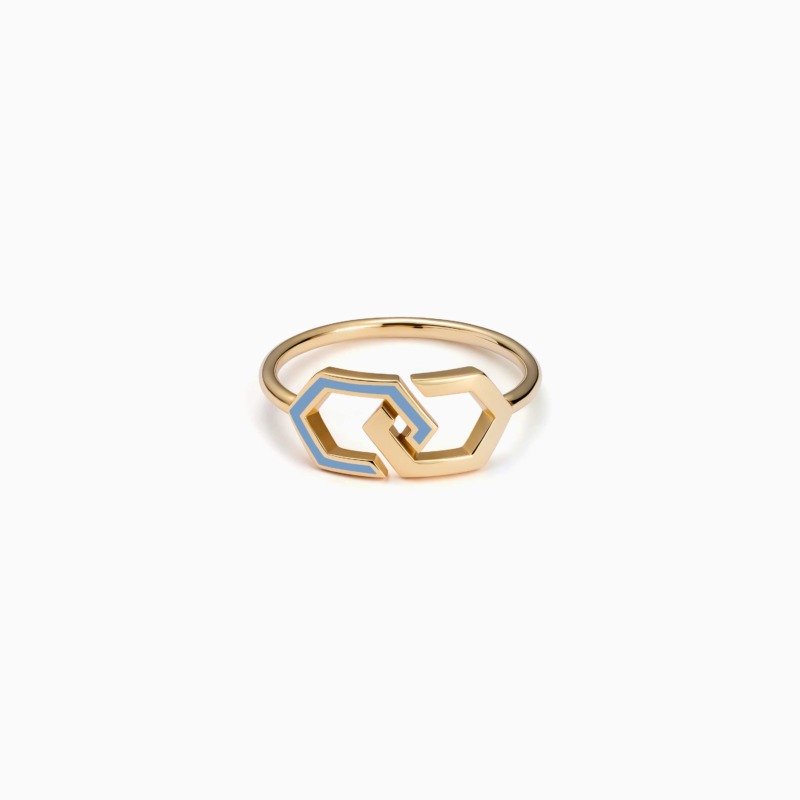A gold Infinity enamel ring band with blue accents rests on a white background, its interlocking geometric shape creating a sleek modern finish.