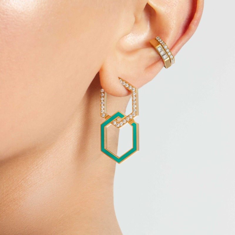 A turquoise enamel infinity earring with gold links and diamond accents hangs from an ear in a close-up jewellery shot by Yataghan Jewellery.