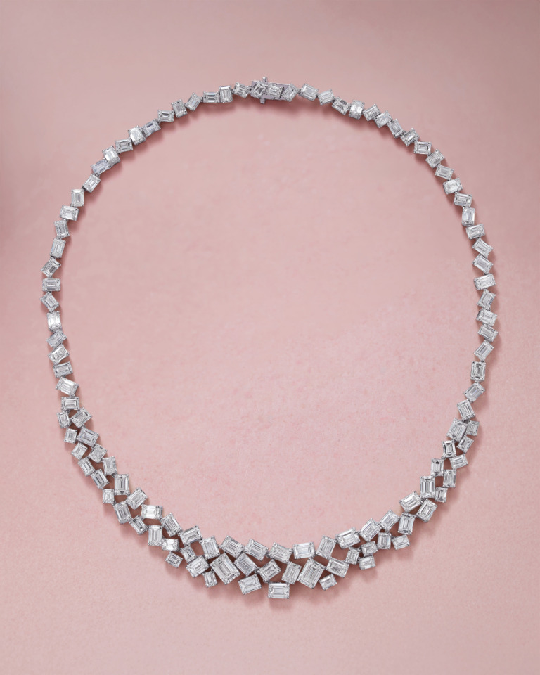 A Yataghan High Jewellery necklace with emerald-cut diamonds forms a graceful curve of 50.91 ct stones in layered settings against a soft blush background.