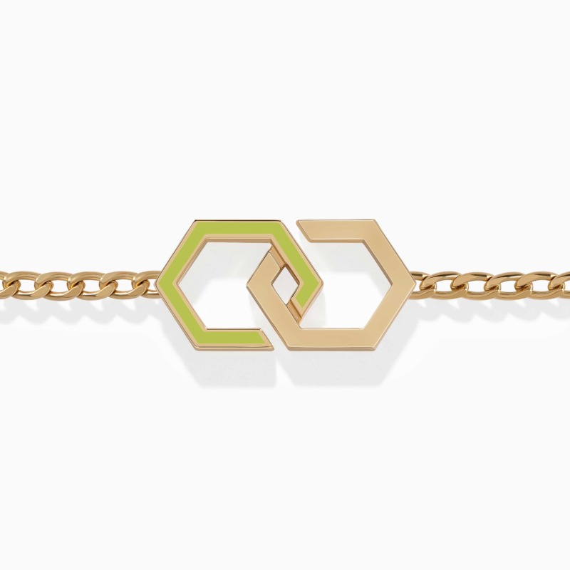 A gold chain bracelet with interlocking hexagon links and neon green enamel accents rests against a clean white background.