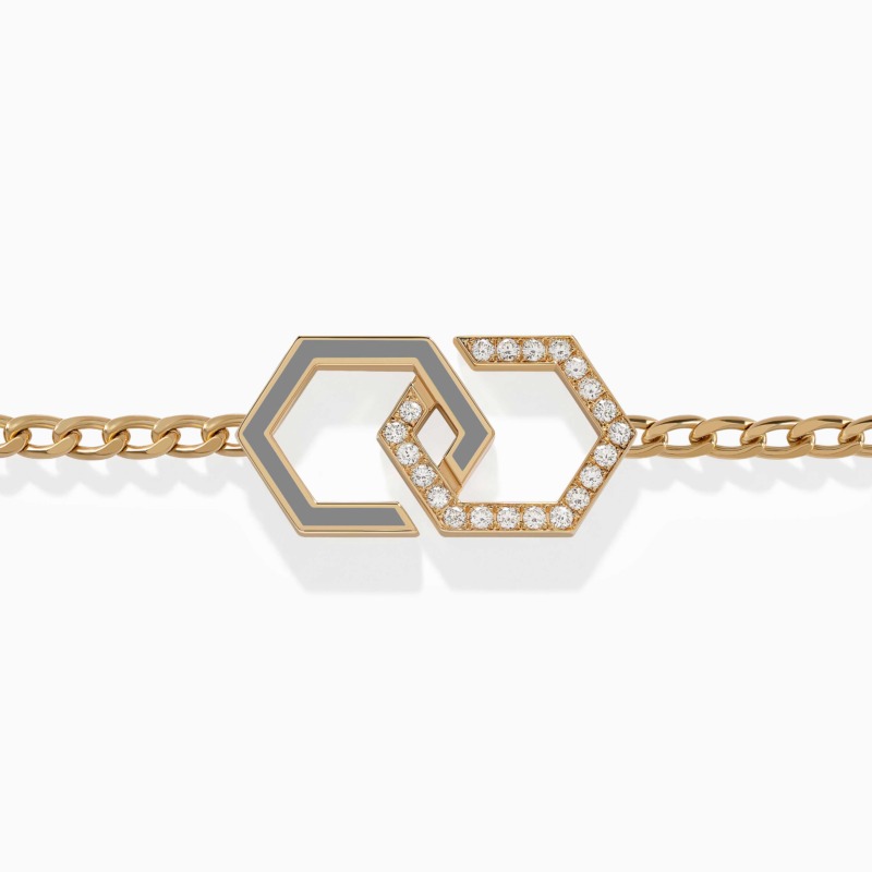 A gold chain bracelet with grey enamel infinity links and diamond-set hexagonal motifs rests against a clean white background in the center.