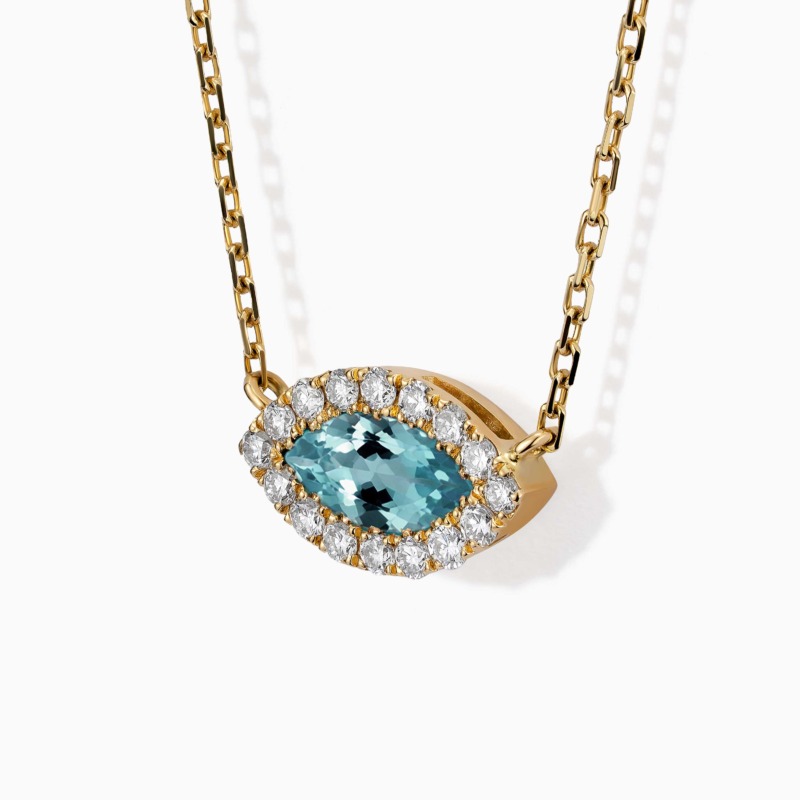 A marquise-cut emerald pendant surrounded by diamonds hangs from a gold chain on a white background.