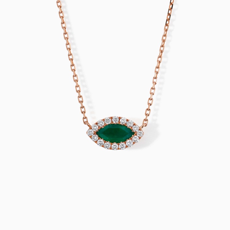 A rose gold necklace with a marquise emerald center stone surrounded by diamonds hangs against a white background.