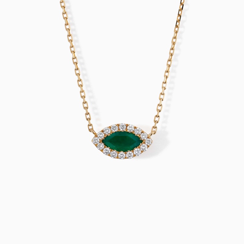 A gold chain necklace with a marquise green emerald center stone surrounded by diamonds on a white background.