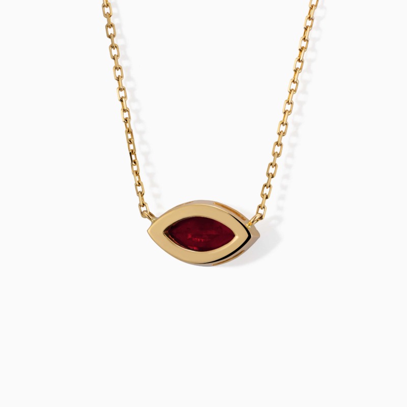 A gold chain necklace with a marquise eye-shaped pendant and deep red gemstone from The Eye collection.
