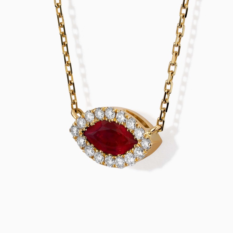 A gold Eye necklace with an oval red gemstone pendant bordered by diamonds hangs against a white background.
