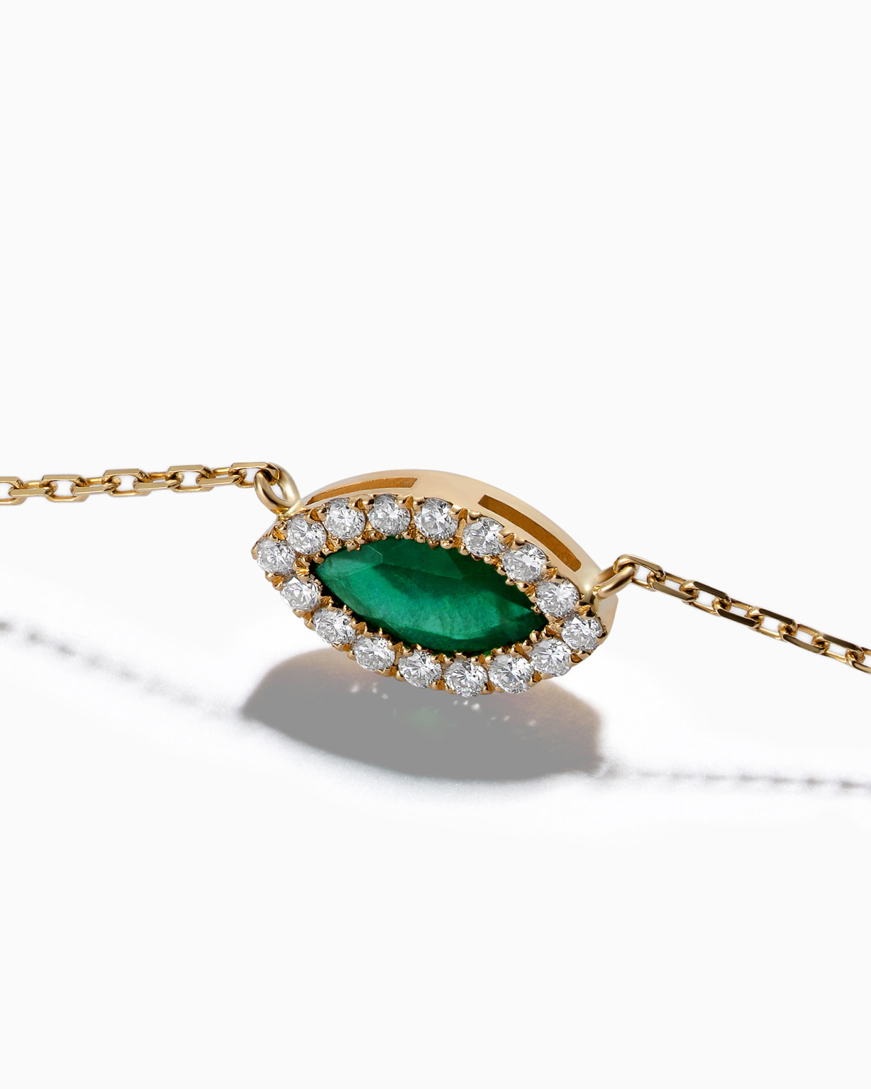 Gold Eye necklace with a green marquise gemstone and a halo of white diamonds on a fine chain.